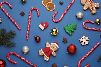 Flat lay composition with sweet candy canes and Christmas decor on blue background