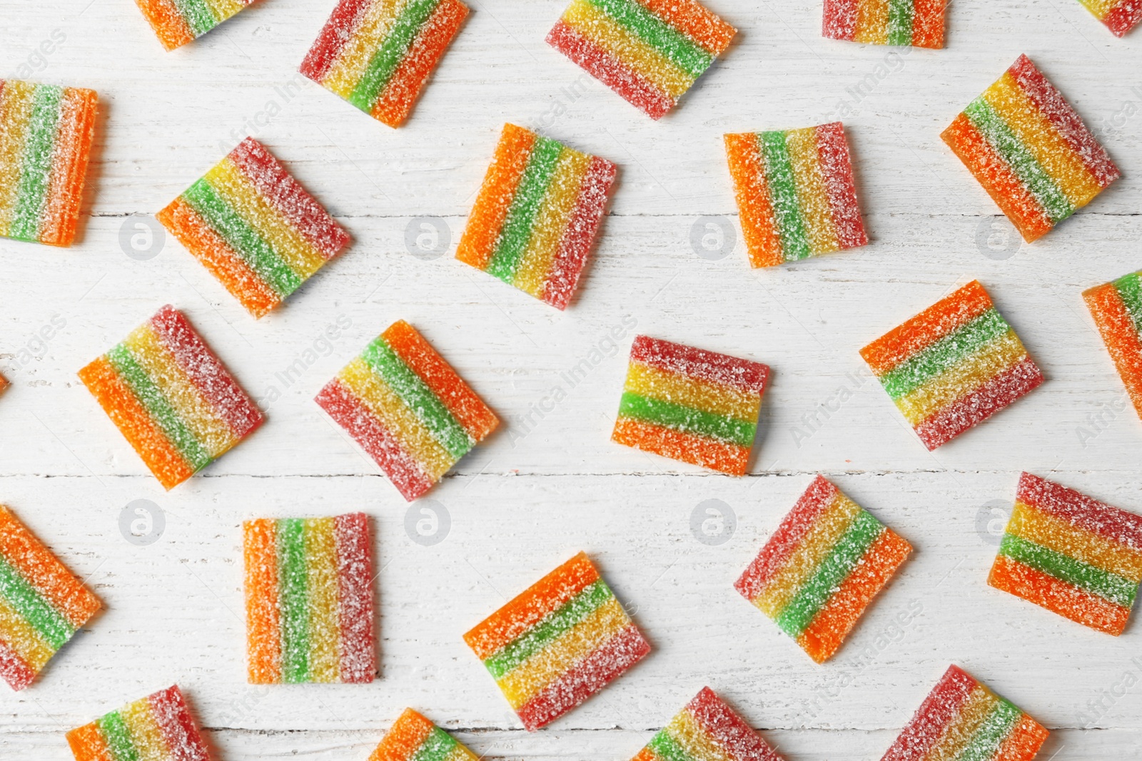 Photo of Tasty jelly candies on white wooden table, flat lay