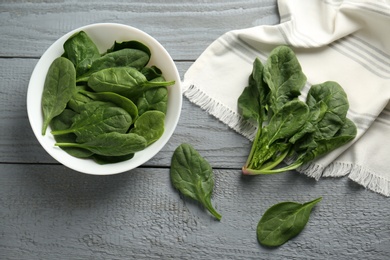 Photo of Fresh green healthy spinach leaves on grey wooden table, flat lay