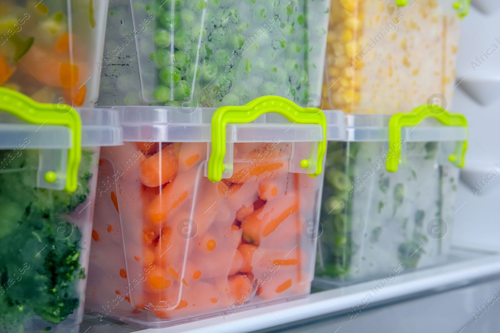 Photo of Containers with deep frozen vegetables in refrigerator