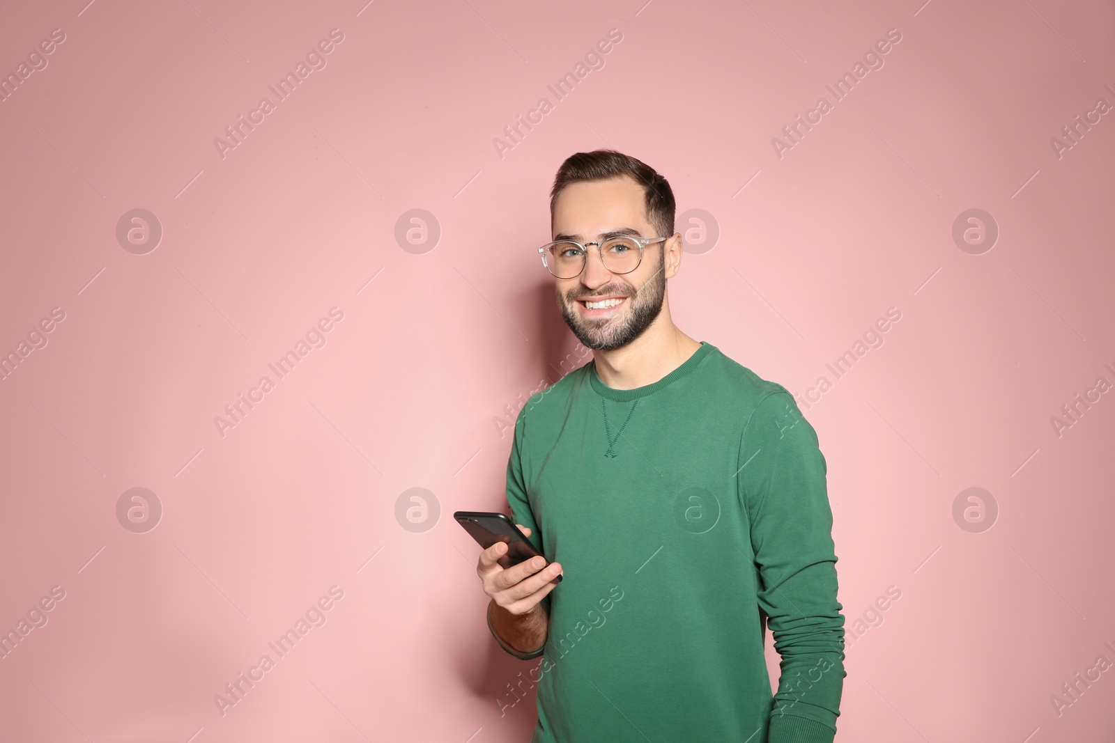 Photo of Handsome young man with mobile phone on color background