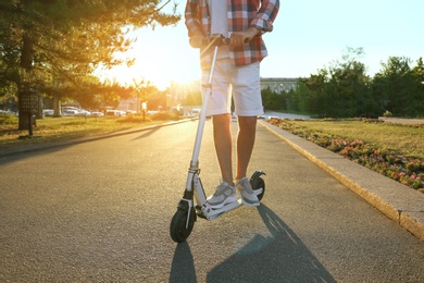 Photo of Man riding modern kick scooter in park, closeup