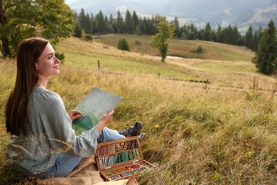 Photo of Young woman drawing landscape with soft pastels in nature. Space for text