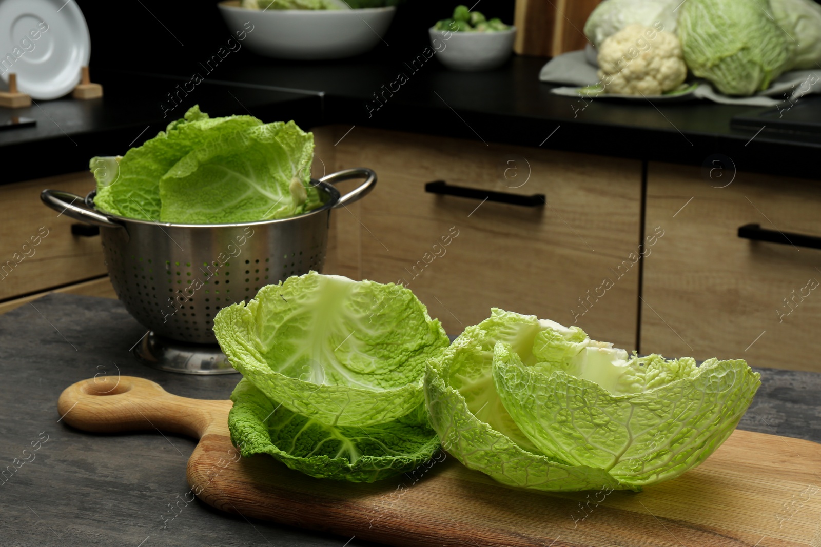 Photo of Fresh Savoy cabbage leaves on black table in kitchen