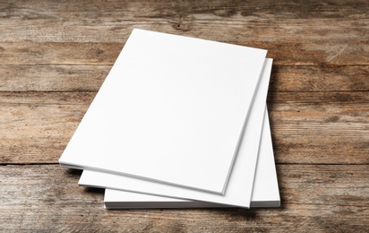 Photo of Stack of blank paper sheets for brochure on wooden background. Mock up