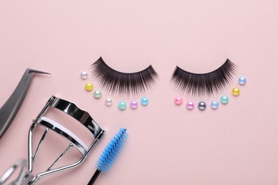 Photo of Flat lay composition with false eyelashes and cosmetic tools on pink background