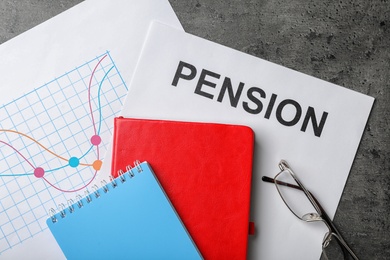 Photo of Notebooks, chart, glasses and paper with word PENSION on table, flat lay