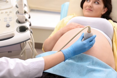 Photo of Young pregnant woman undergoing ultrasound scan in clinic