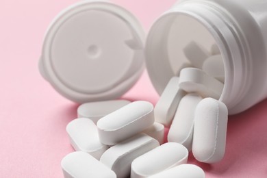 Photo of Bottle and vitamin capsules on pink background, closeup