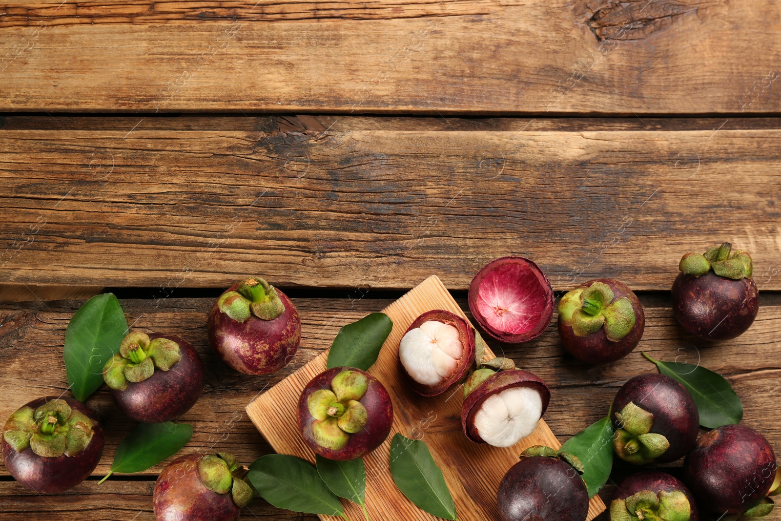 Photo of Fresh ripe mangosteen fruits on wooden table, flat lay. Space for text