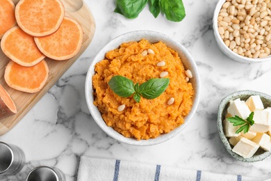 Flat lay composition with bowl of sweet potato puree and ingredients on marble table