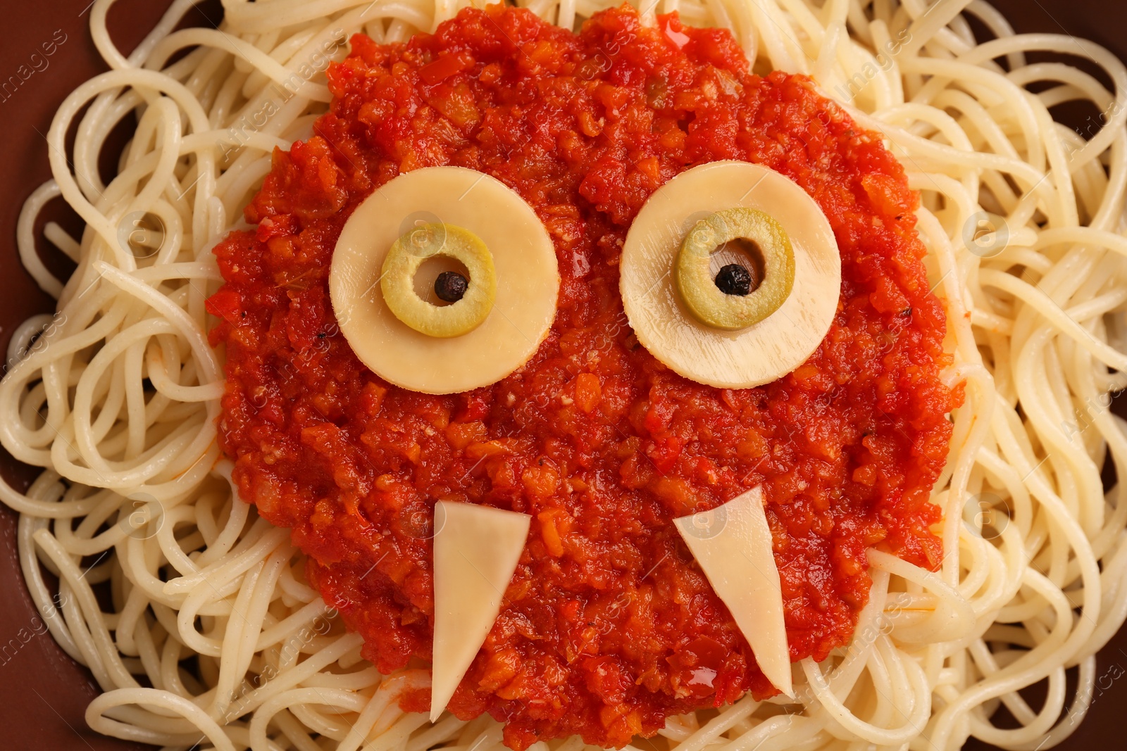 Photo of Funny monster made of tasty pasta on plate, top view. Halloween food