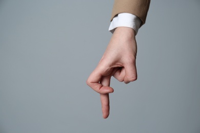 Businesswoman imitating walk with hand on grey background, closeup. Finger gesture
