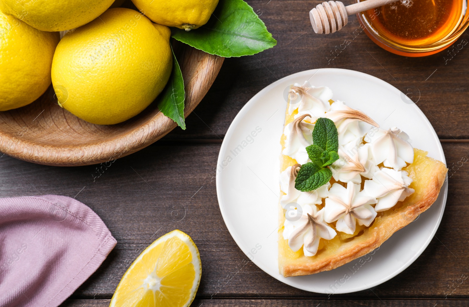 Photo of Piece of delicious lemon meringue pie with mint on wooden table, flat lay