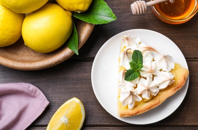 Photo of Piece of delicious lemon meringue pie with mint on wooden table, flat lay