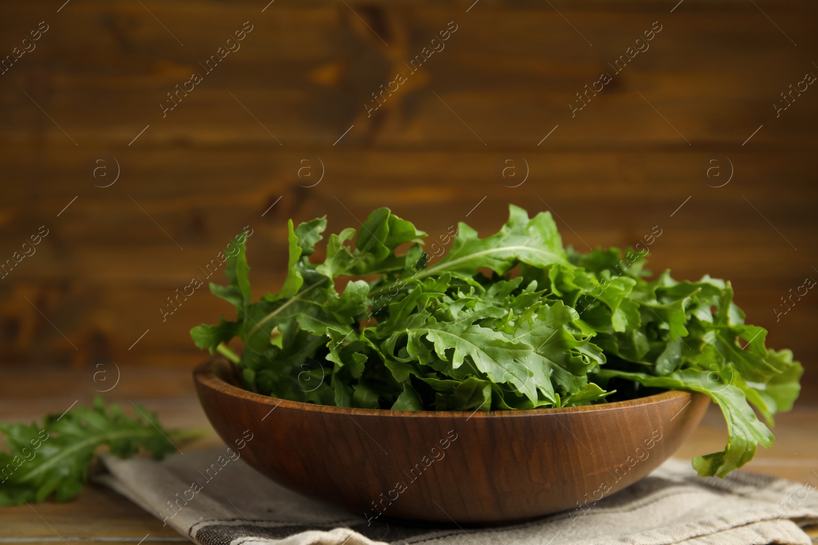 Photo of Fresh arugula in bowl on wooden table