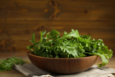 Fresh arugula in bowl on wooden table