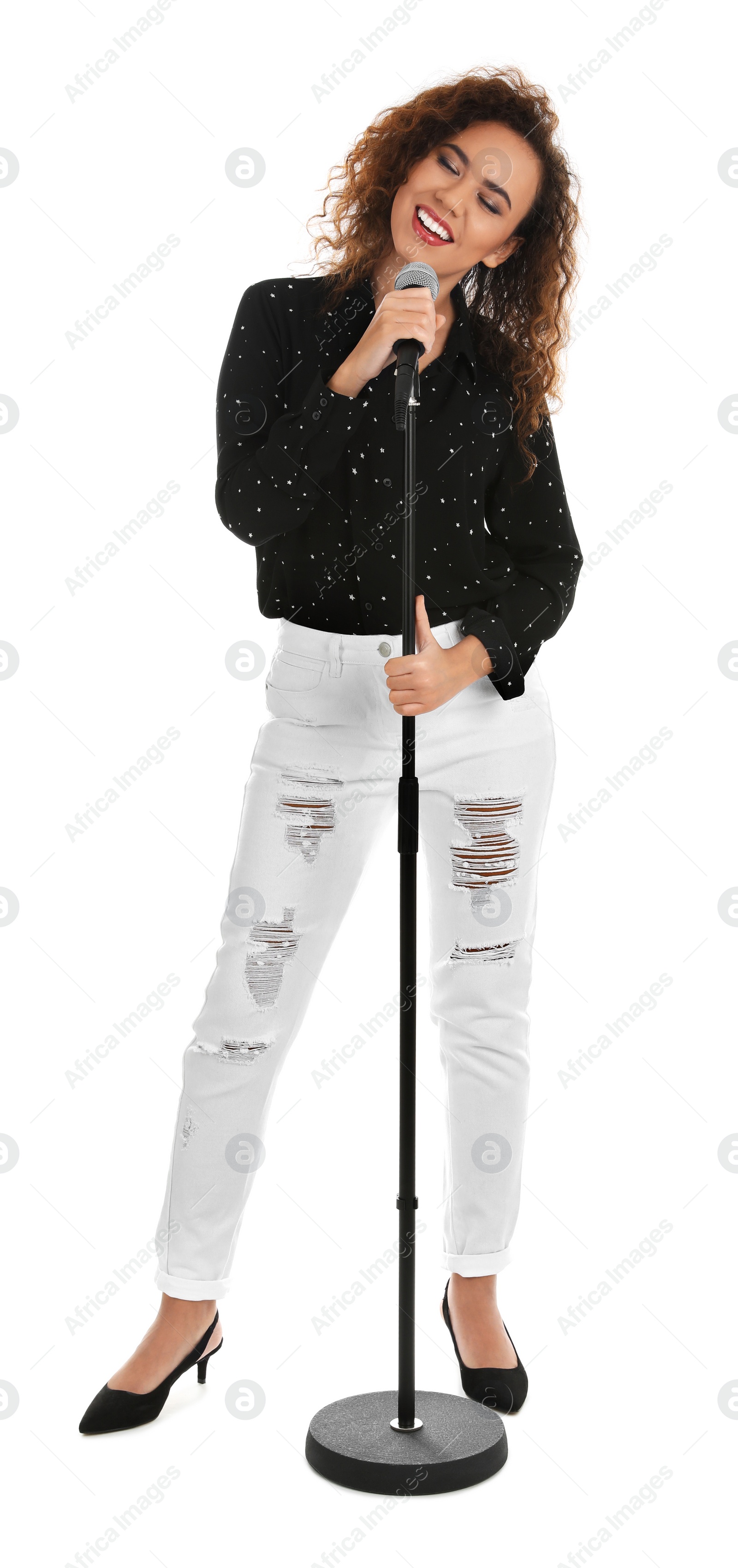 Photo of Curly African-American woman in stylish clothes singing with microphone on white background