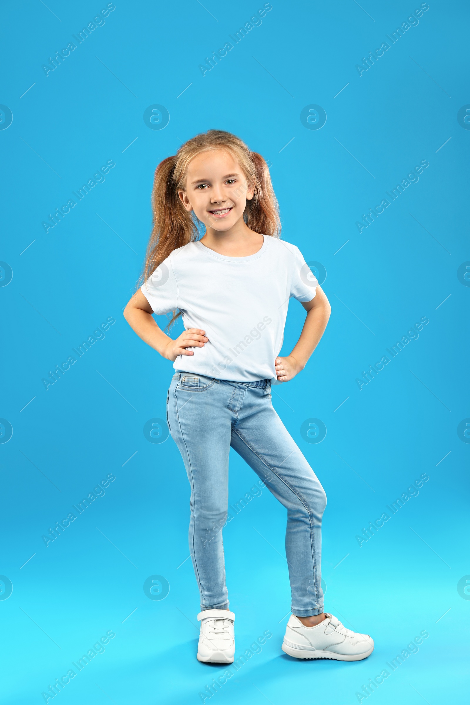 Photo of Cute little girl posing on blue background