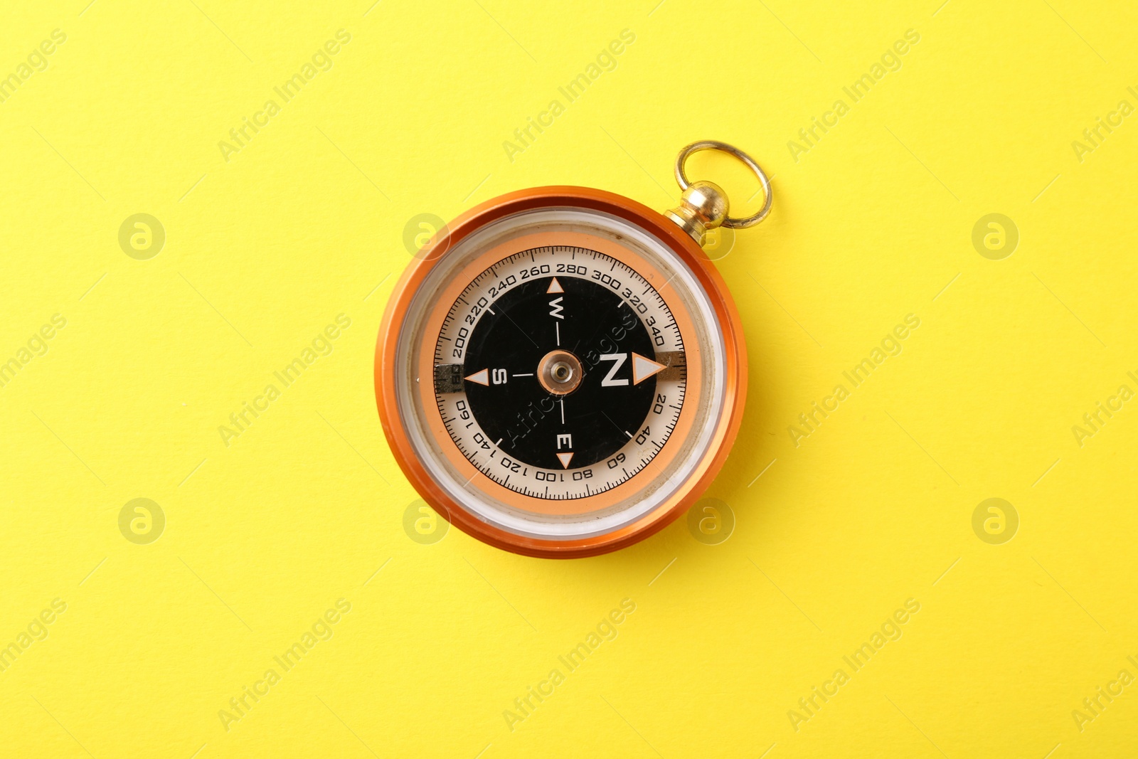 Photo of One compass on yellow background, top view