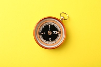 Photo of One compass on yellow background, top view