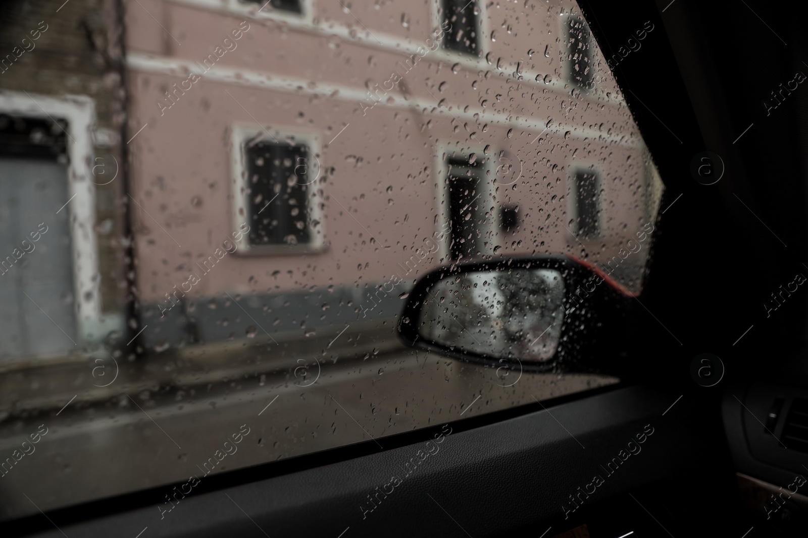Photo of Rainy weather in city, view through car window covered with drops