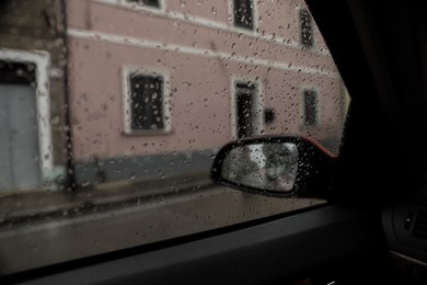Rainy weather in city, view through car window covered with drops