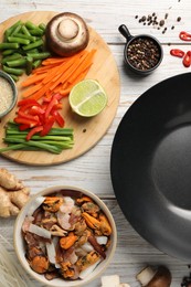 Photo of Flat lay composition with black wok and products on light wooden table