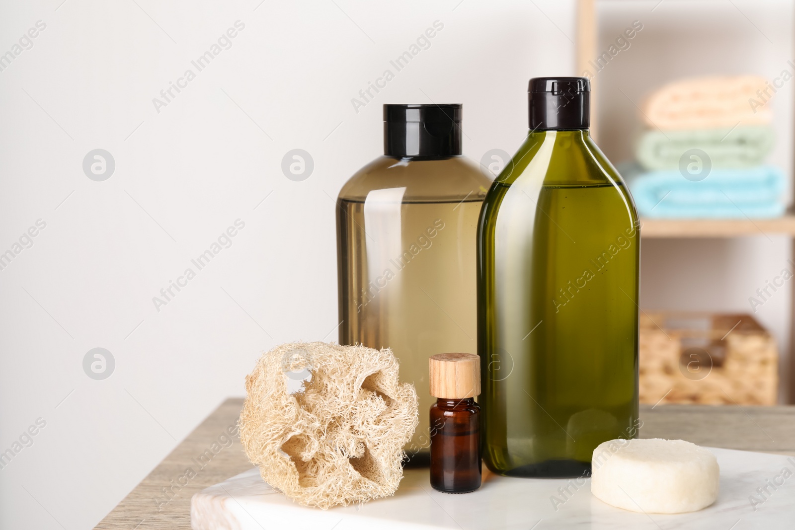 Photo of Solid shampoo bar and bottles of cosmetic product on wooden table in bathroom, space for text