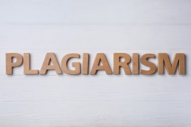 Word Plagiarism made of wooden letters on white table, flat lay