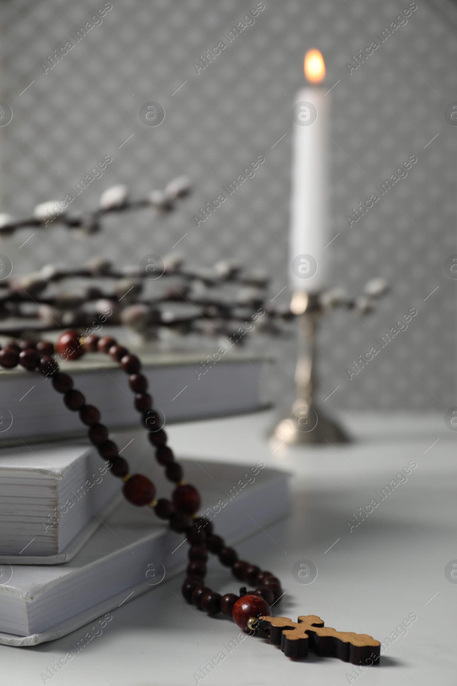 Photo of Rosary beads, books and willow branches on white table, closeup