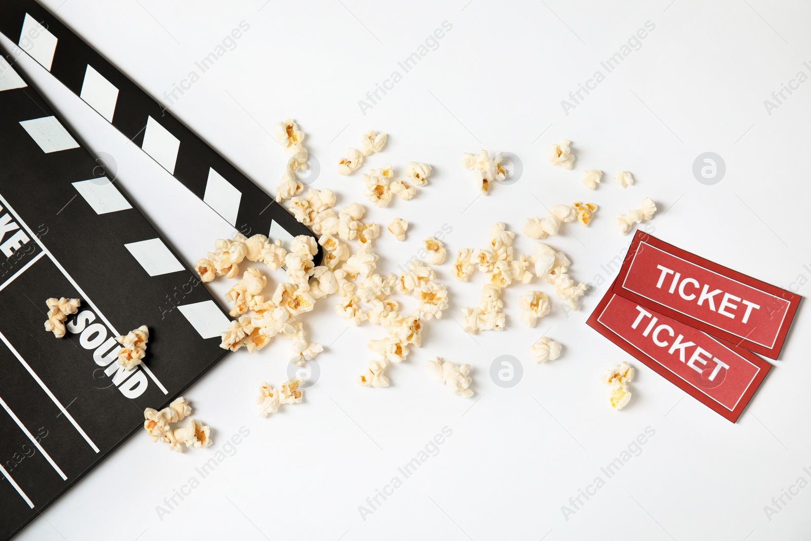 Photo of Clapperboard, popcorn and tickets isolated on white, top view. Cinema snack