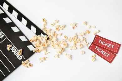 Photo of Clapperboard, popcorn and tickets isolated on white, top view. Cinema snack