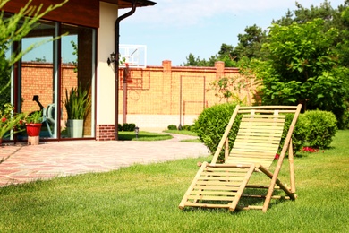 Wooden deck chair in beautiful garden on sunny day