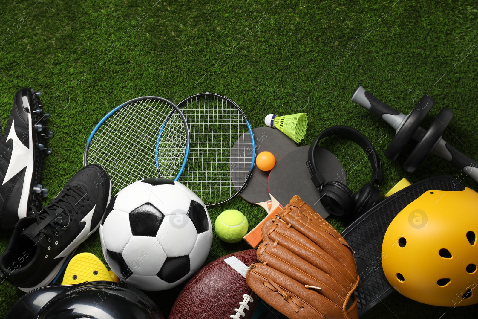 Photo of Different sports equipment on green grass, flat lay