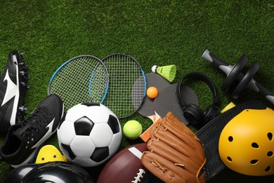 Photo of Different sports equipment on green grass, flat lay