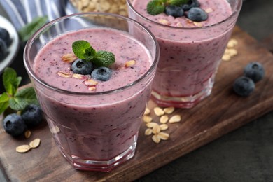 Photo of Glasses of tasty blueberry smoothie with oatmeal on wooden board