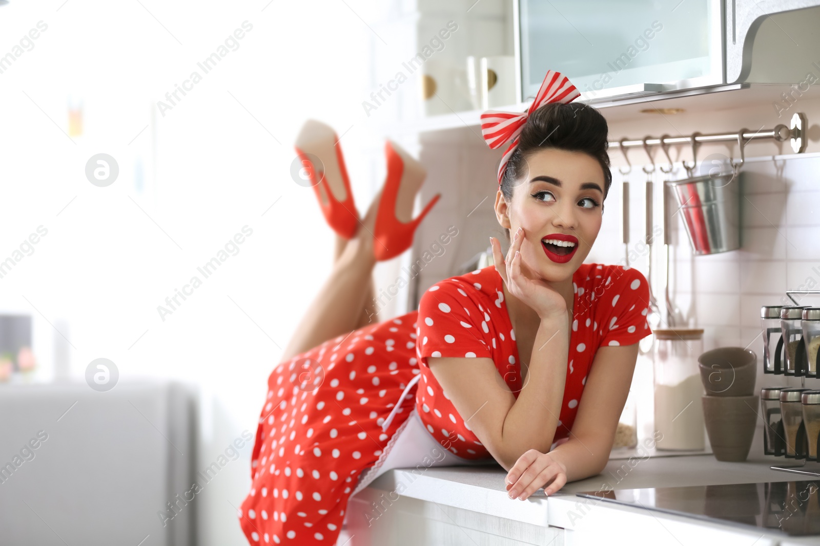 Photo of Funny young housewife lying on kitchen counter