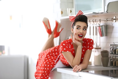 Funny young housewife lying on kitchen counter