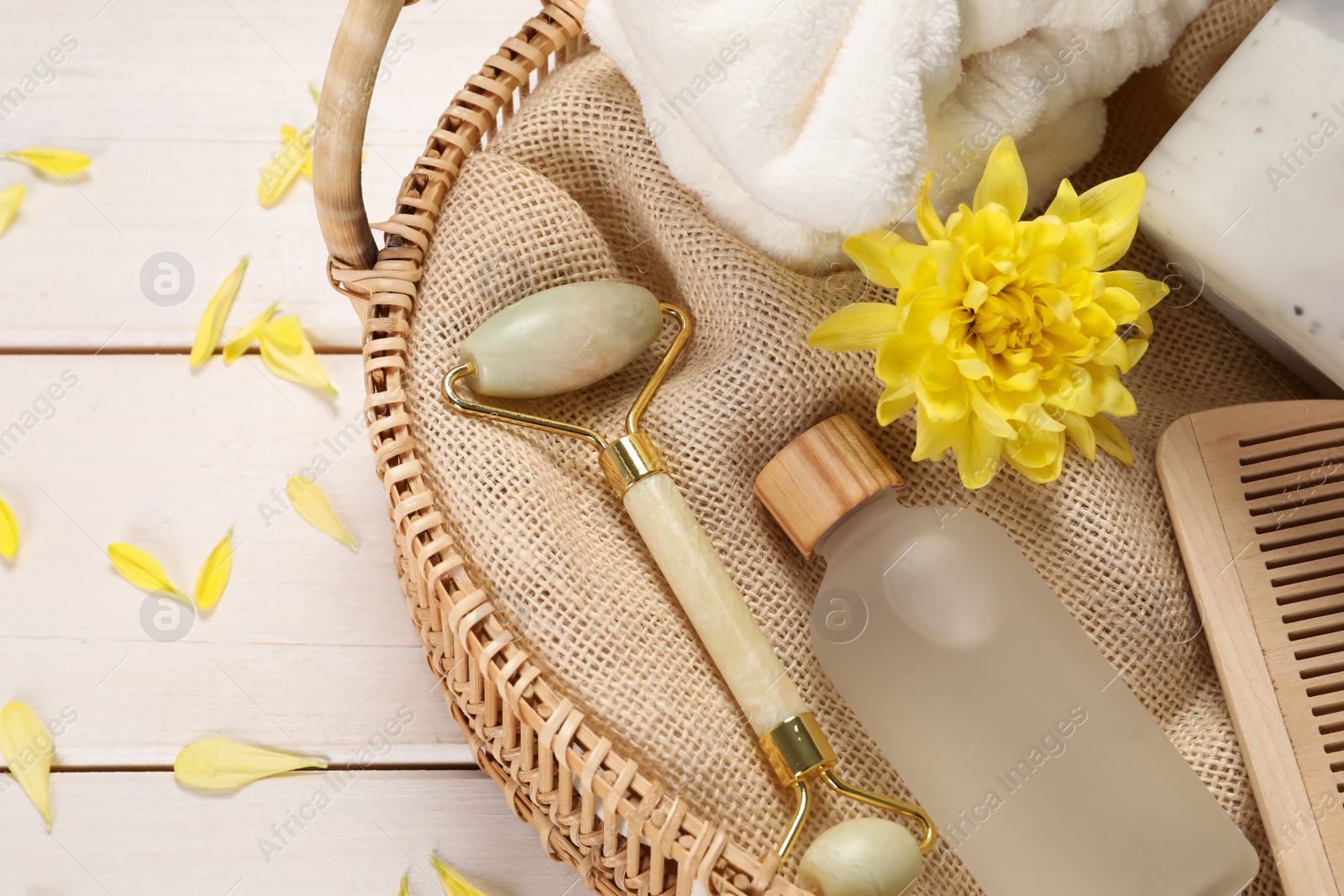 Photo of Spa gift set with different products in wicker basket on white wooden table, flat lay