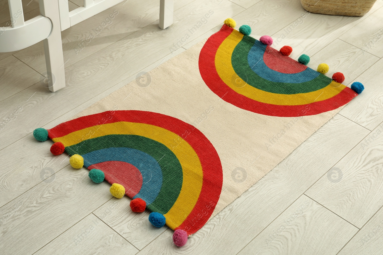 Photo of Stylish rug with rainbow on floor indoors