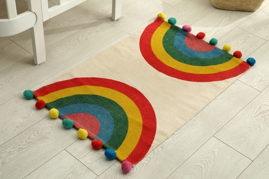 Stylish rug with rainbow on floor indoors