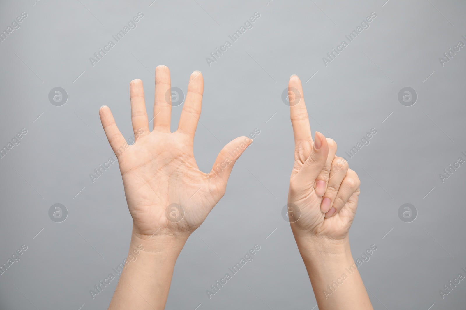 Photo of Woman showing sign six on grey background, closeup. Body language