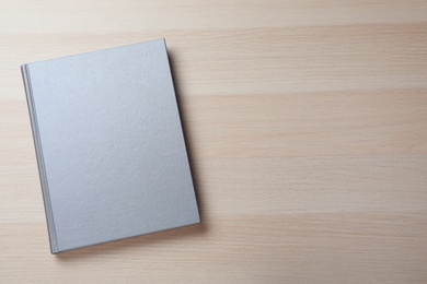 Closed grey book with hard cover on wooden table, top view. Space for text