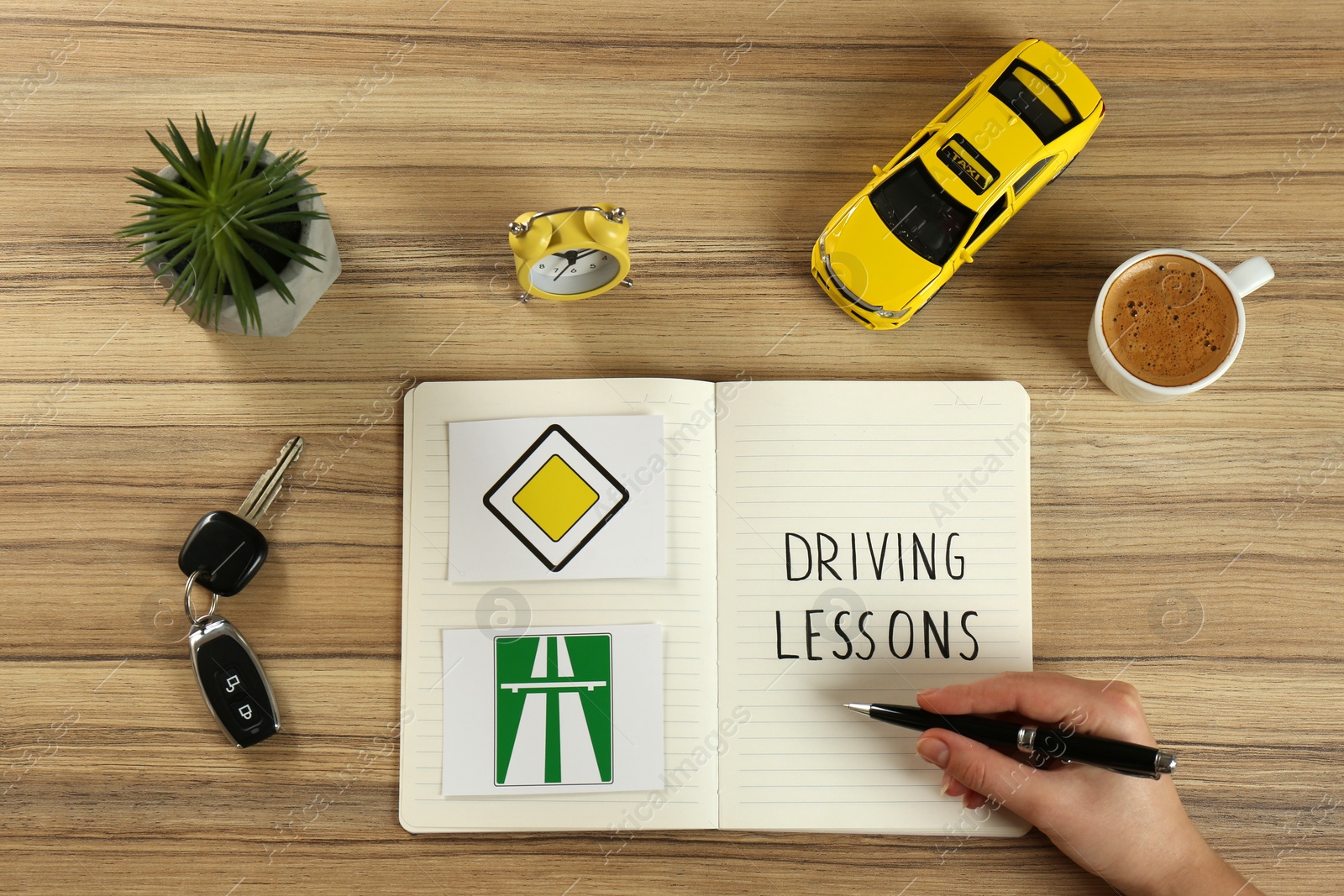 Photo of Woman with workbook for driving lessons and road signs at wooden table, top view. Passing license exam