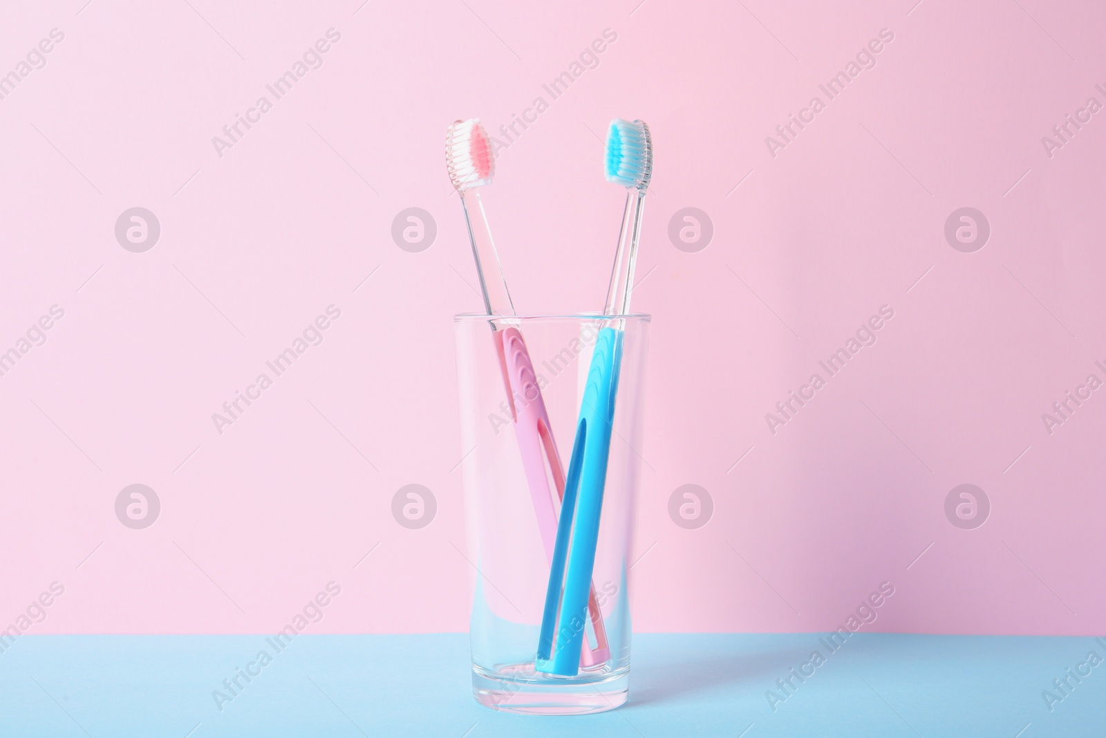 Photo of Cup with toothbrushes on table against color background. Dental care