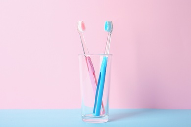 Photo of Cup with toothbrushes on table against color background. Dental care