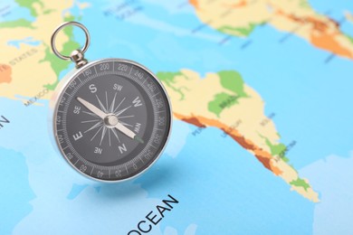 Photo of One compass on world map, space for text. Tourist equipment