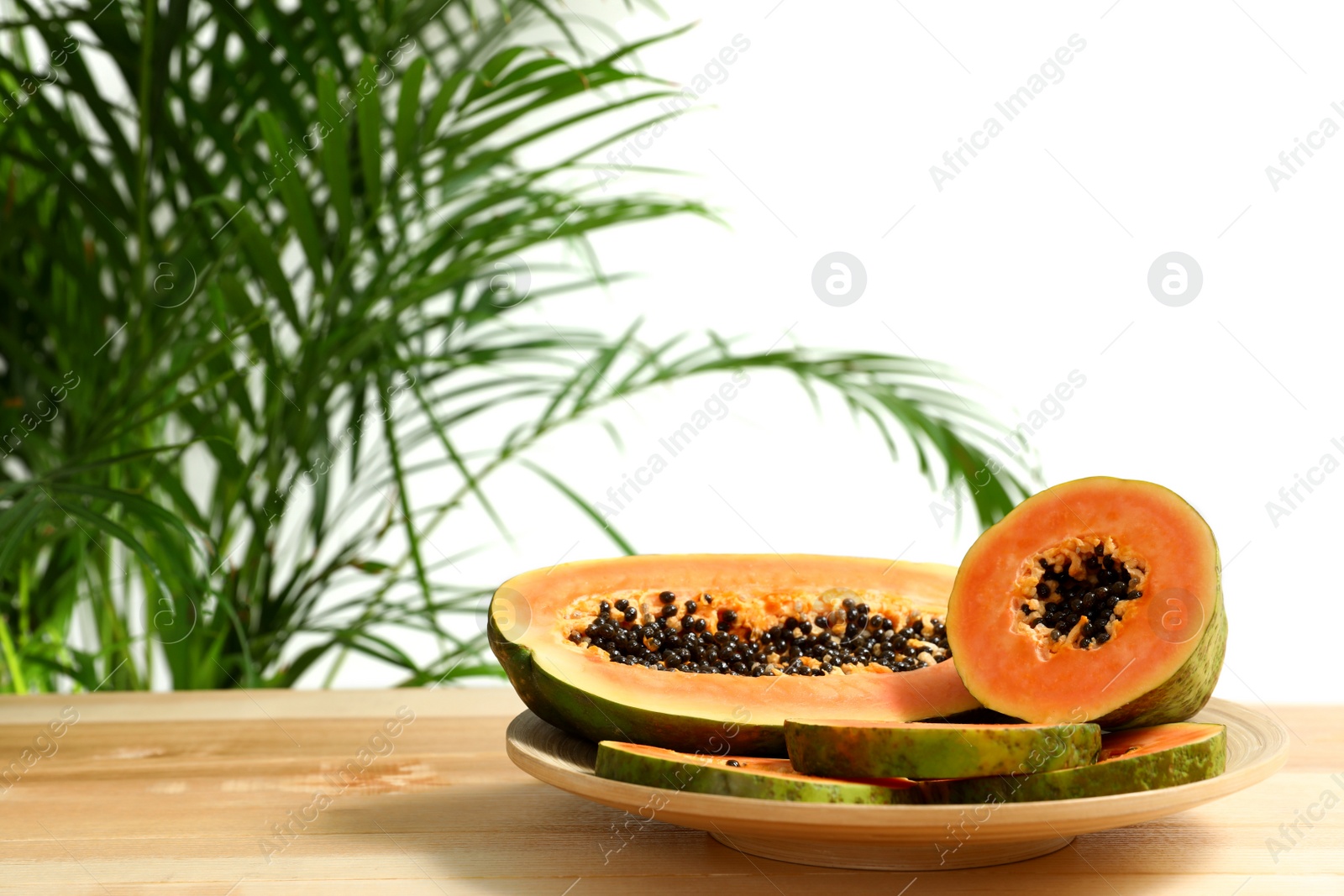 Photo of Fresh juicy papayas on wooden table against blurred background, space for text