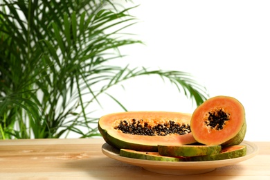 Photo of Fresh juicy papayas on wooden table against blurred background, space for text